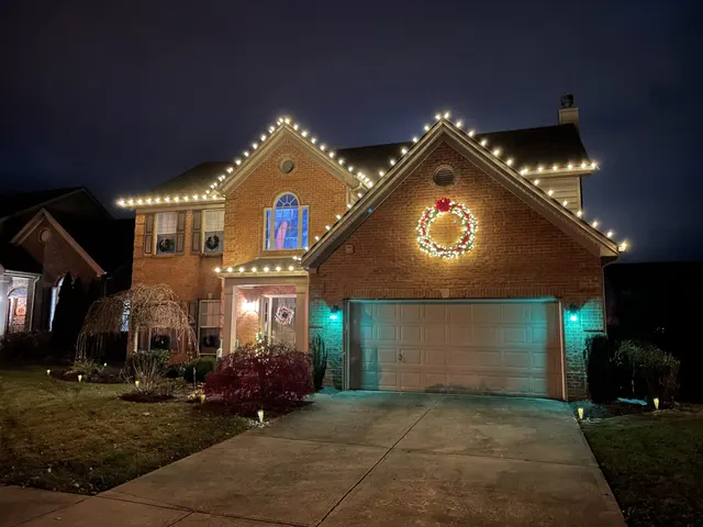 Christmas roofline lights and an illuminated wreath above a garage