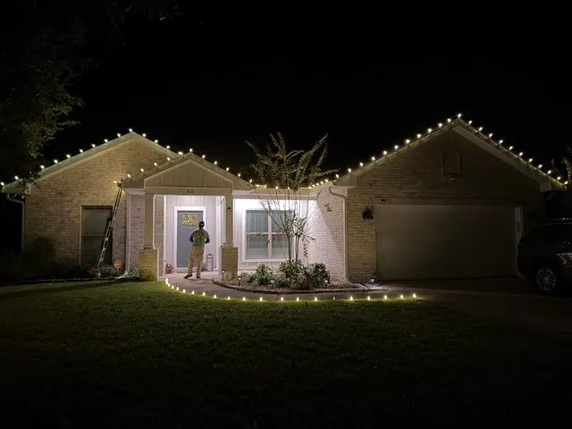 Holiday lights framing a brick home and its entry