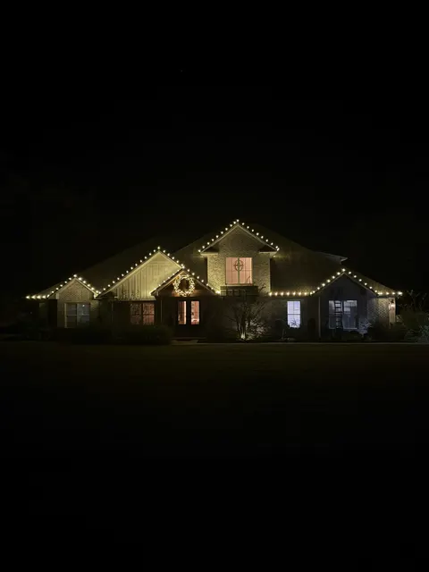 Distant view of a home outlined in Christmas lights