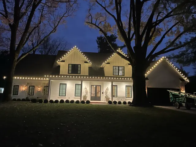 Two-story home with Christmas roofline and ground-level lights