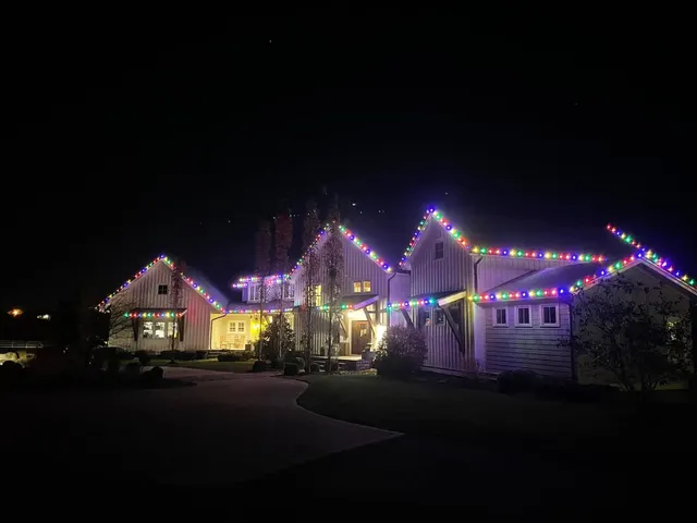 Multicolored Christmas roofline lights across a home and garages