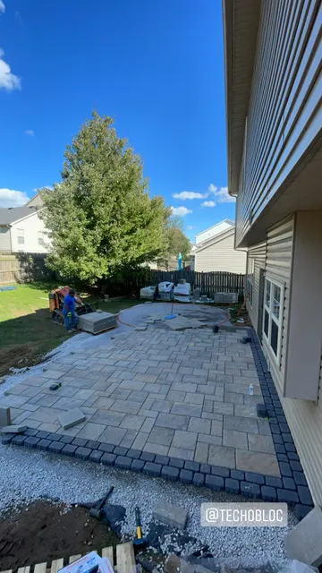 Pavers being installed along the back of a home