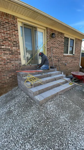 Stone steps and prepared gravel base beside a brick home