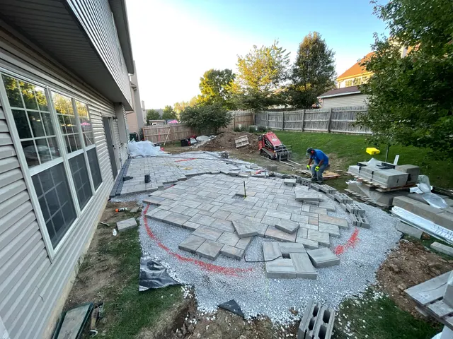 Paver installation and materials beside a backyard patio